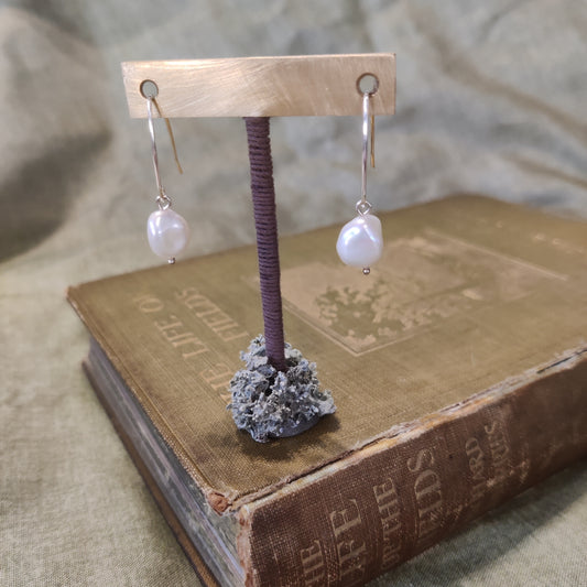 dangling pearl earrings on stand