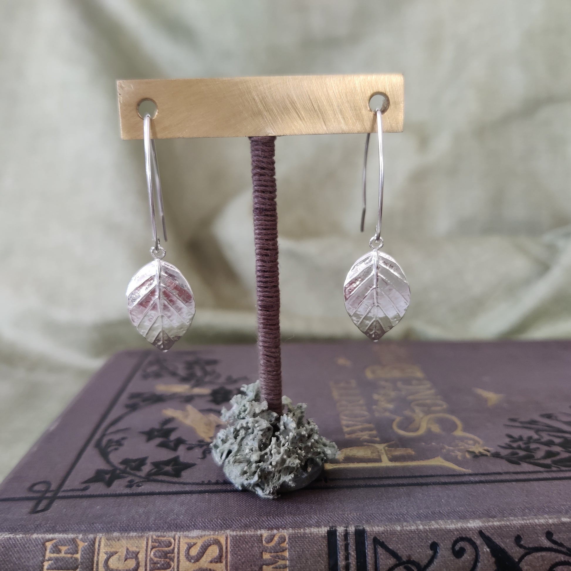 leaf drop earrings handmade in sterling silver on a stand