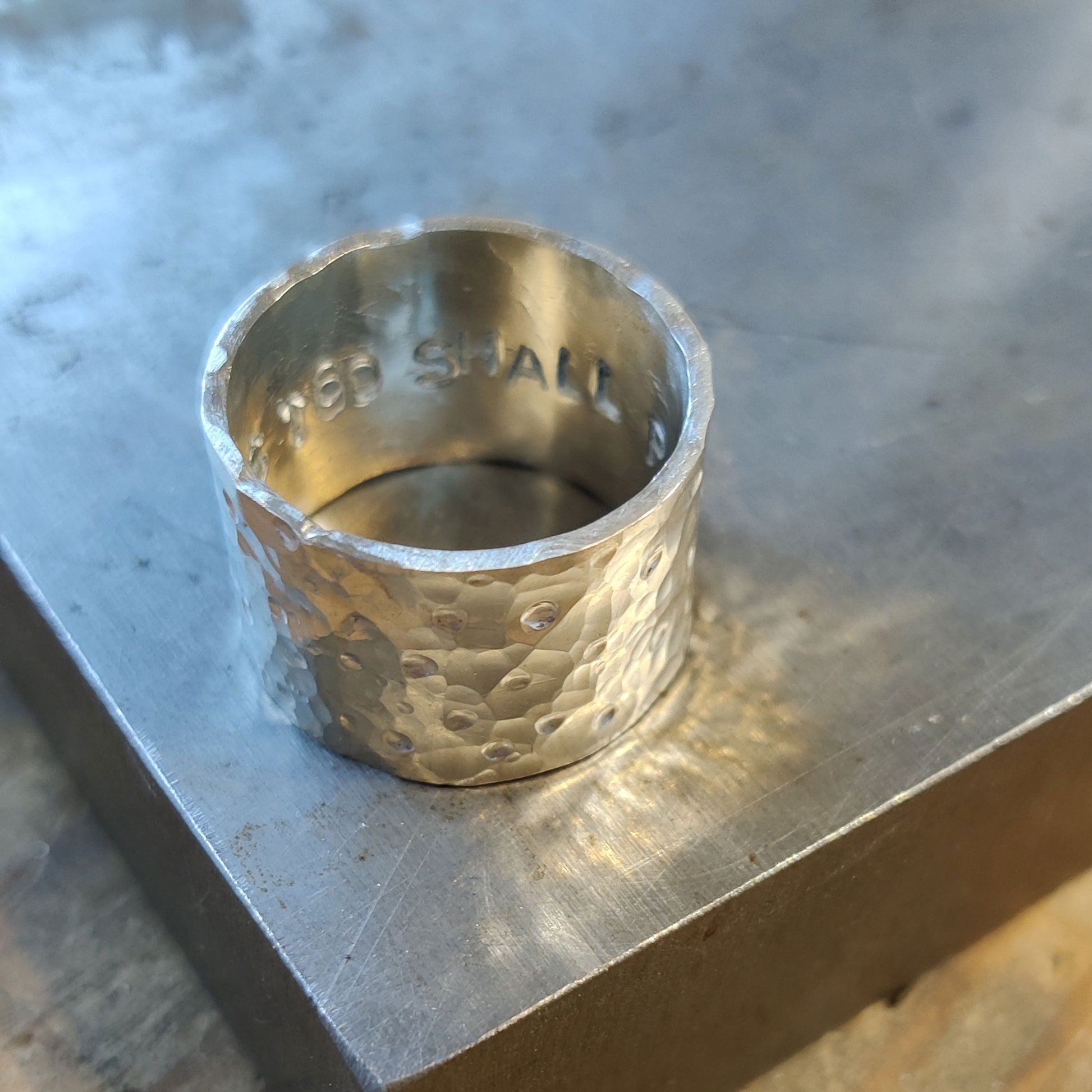 Silver ring with textured design on a metallic surface