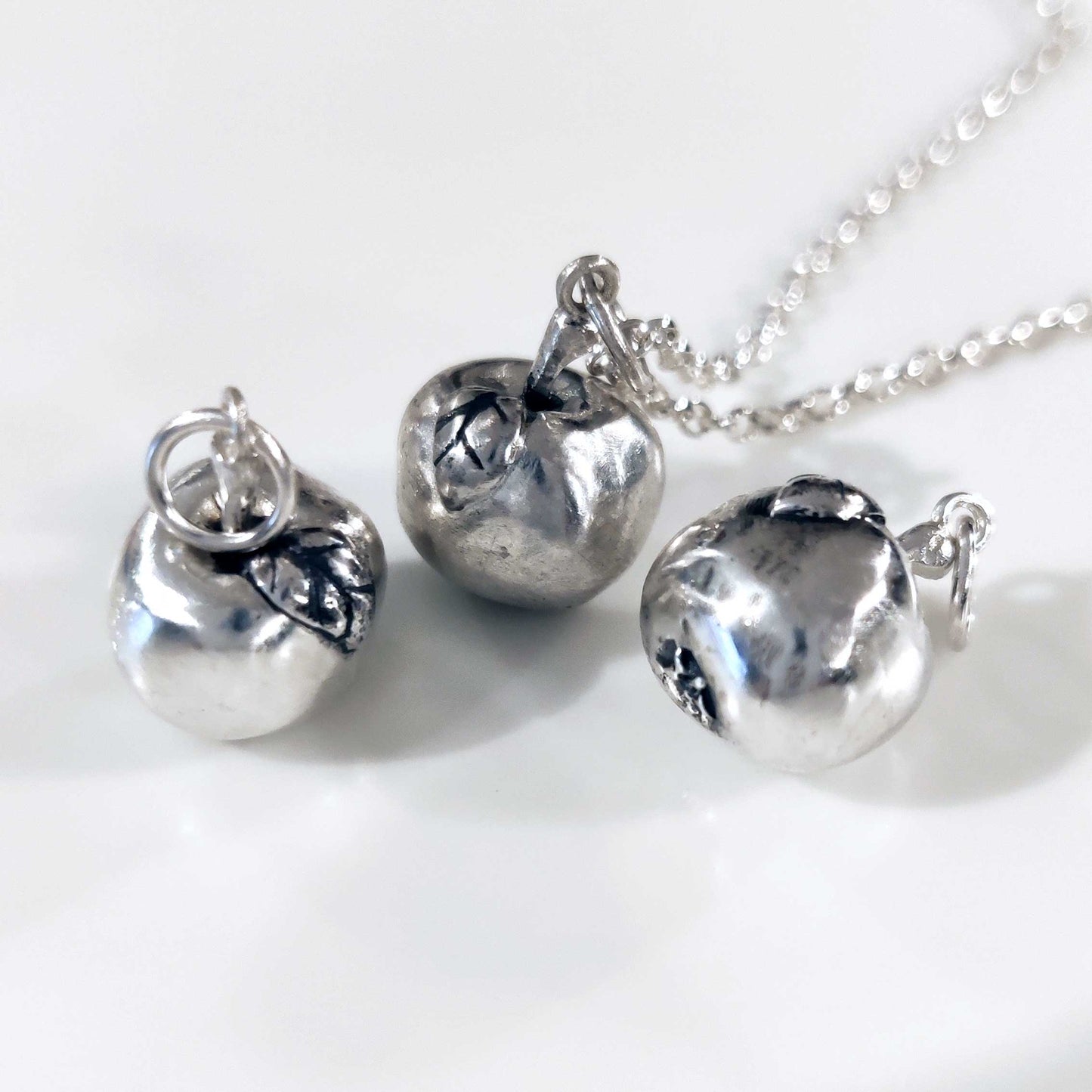 Three solid silver apple pendants
